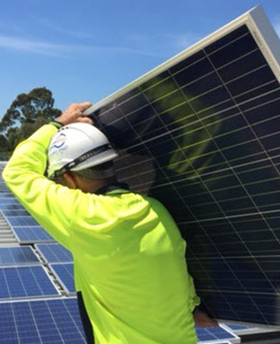 A construction worker moves a solar panel